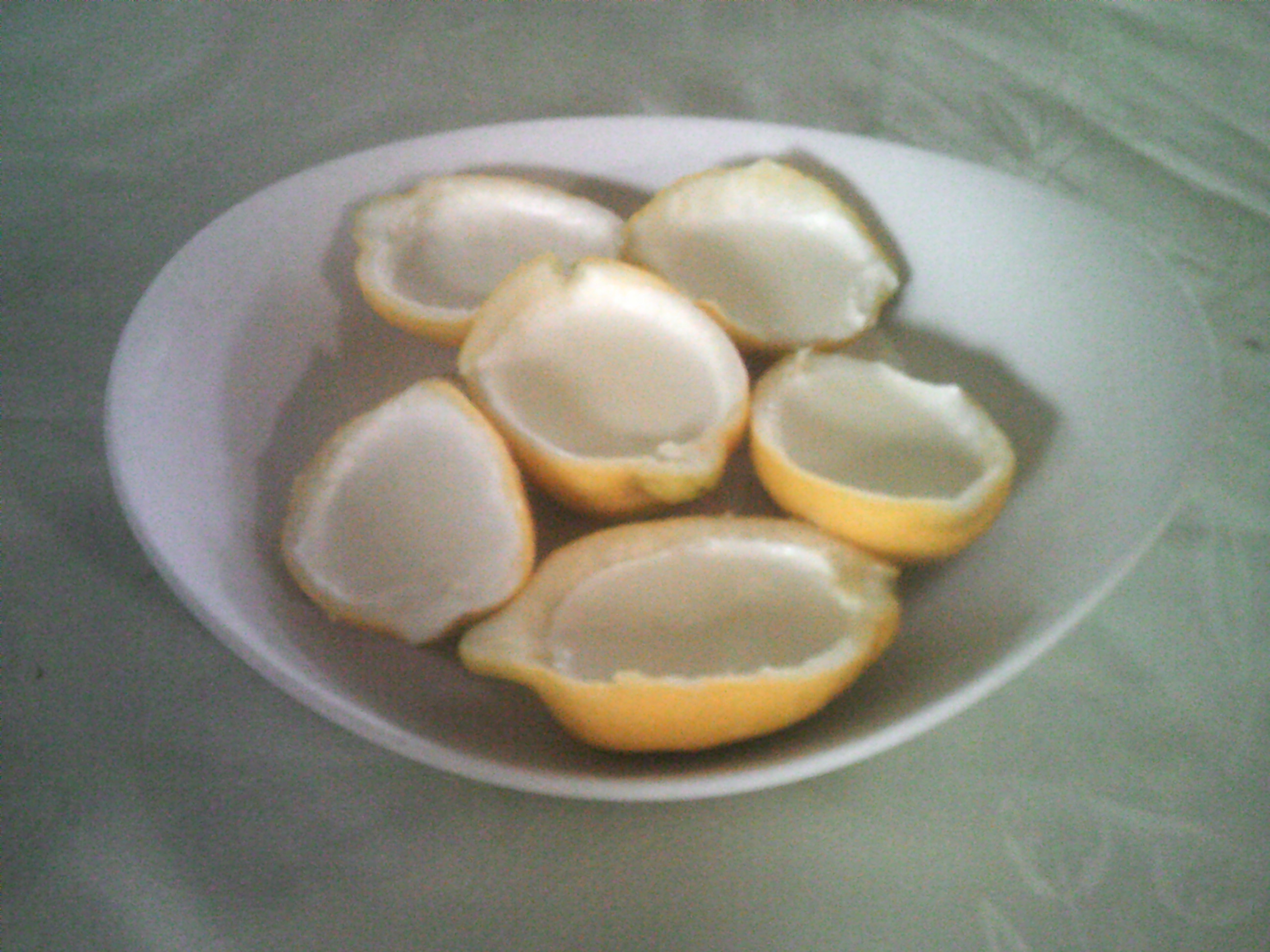 A plate with 6 lemons containing lemon posset on a green background.