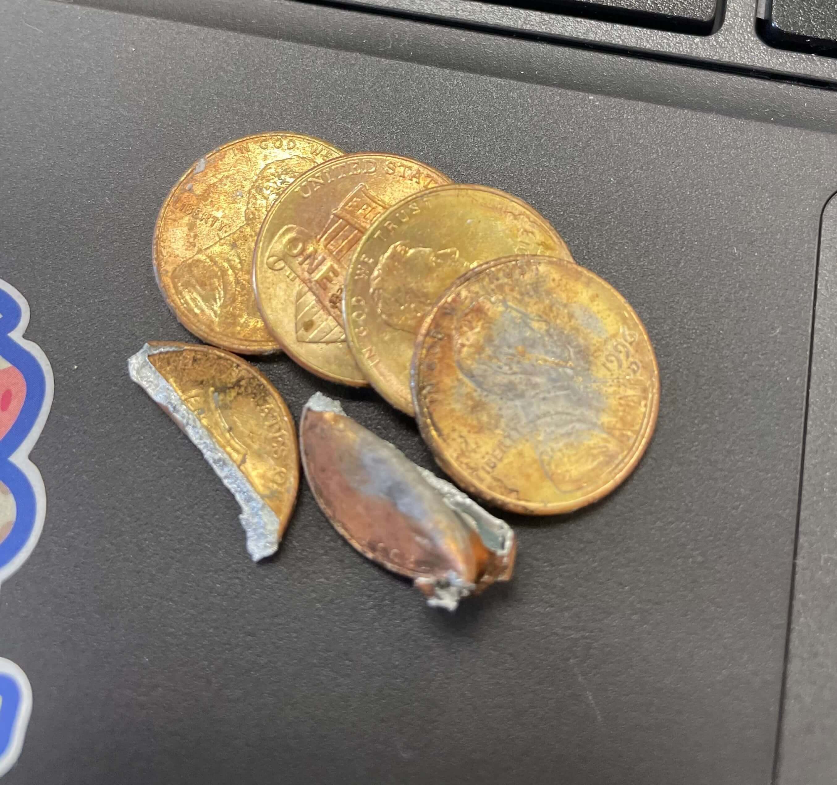 Close up of brass-coated pennies lying on a laptop.